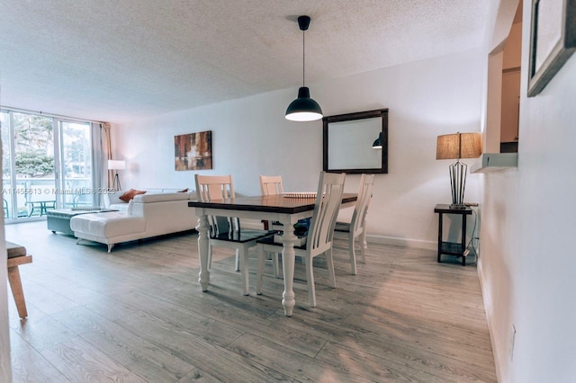 dining space featuring a textured ceiling, light hardwood / wood-style floors, and floor to ceiling windows