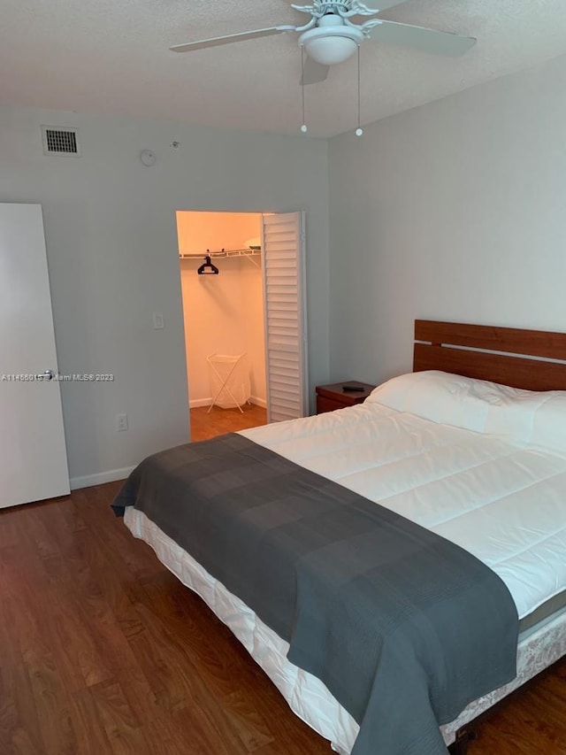 bedroom with hardwood / wood-style floors, a walk in closet, a closet, and ceiling fan