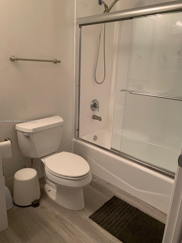 bathroom with shower / bath combination with glass door, toilet, and hardwood / wood-style flooring