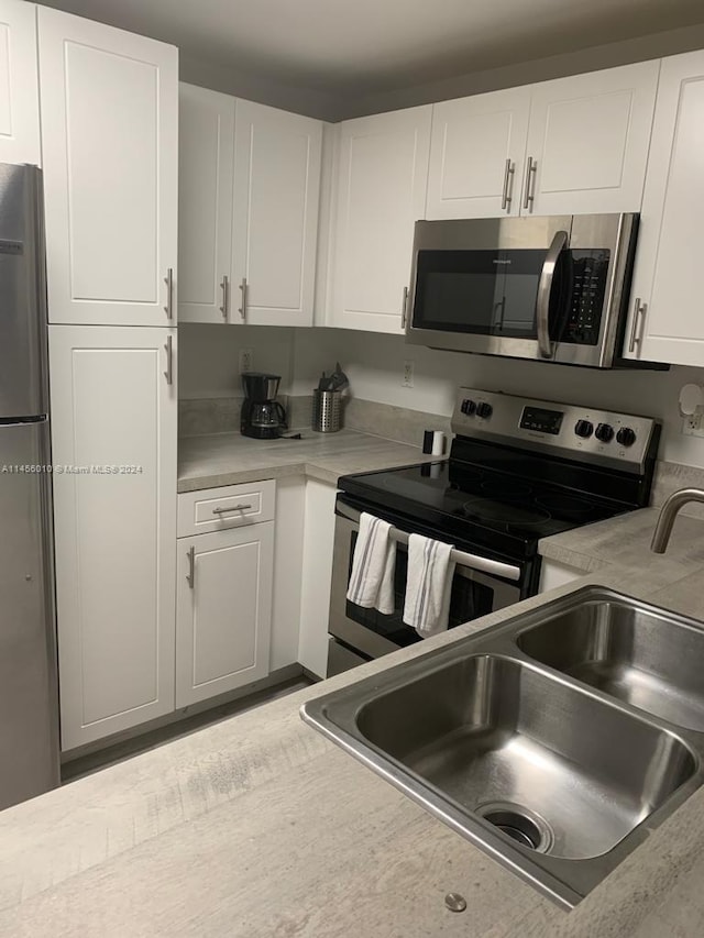 kitchen featuring appliances with stainless steel finishes, white cabinetry, and sink