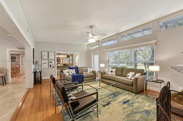 living room with light hardwood / wood-style flooring, ceiling fan, and a textured ceiling