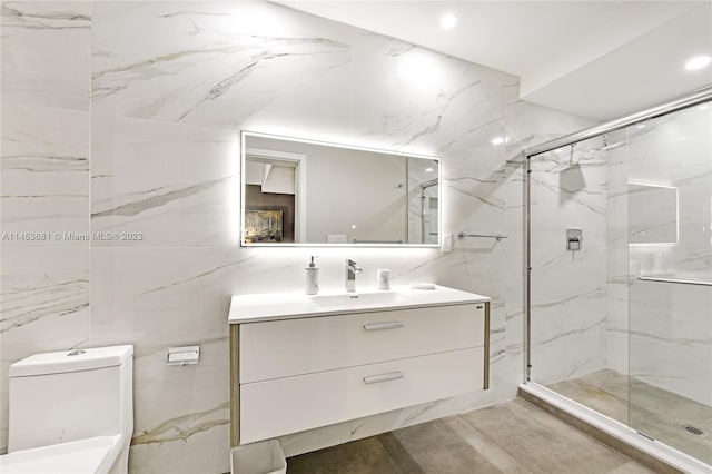 bathroom featuring tile walls, a shower with door, toilet, and oversized vanity