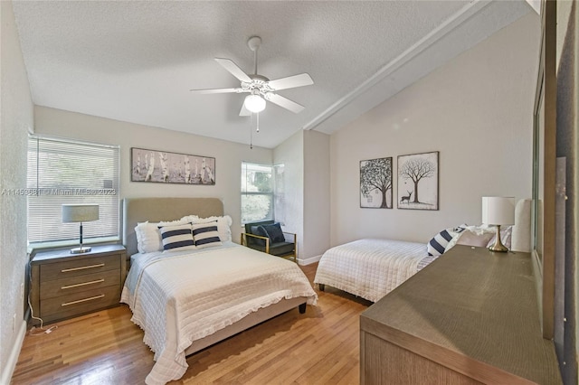 bedroom featuring lofted ceiling, light hardwood / wood-style floors, ceiling fan, and a textured ceiling