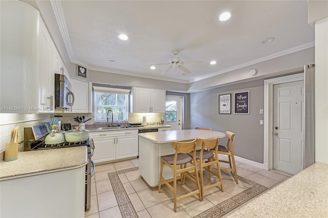 kitchen featuring ornamental molding, stove, ceiling fan, and white cabinetry