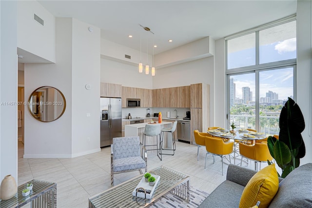 living room with sink, a towering ceiling, and light tile flooring