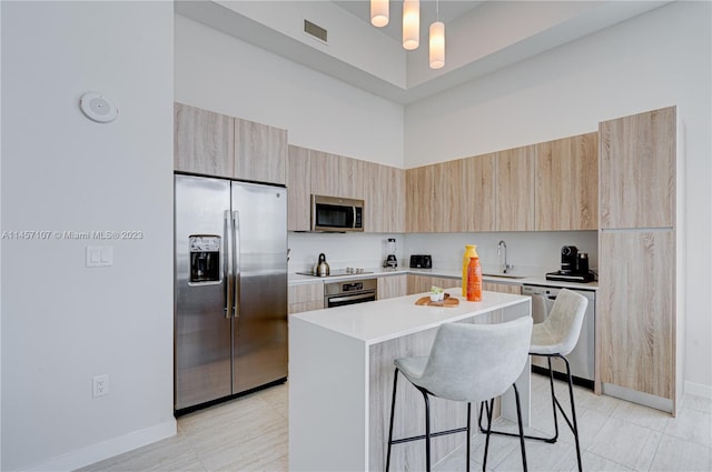 kitchen with a notable chandelier, appliances with stainless steel finishes, a kitchen bar, a center island, and pendant lighting