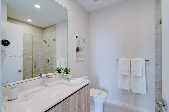 bathroom with vanity, a shower with door, and toilet