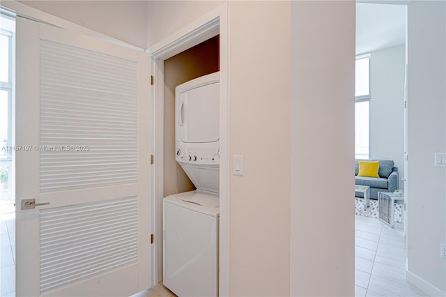 clothes washing area featuring light tile floors and stacked washer and dryer