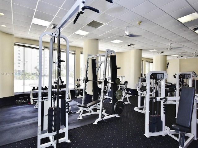 exercise room with plenty of natural light, dark carpet, and a paneled ceiling