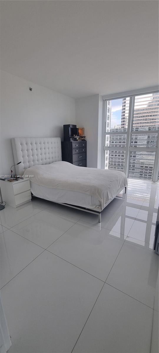 bedroom with light tile flooring and floor to ceiling windows