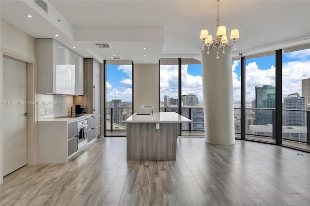 kitchen with floor to ceiling windows, a chandelier, light hardwood / wood-style floors, decorative light fixtures, and white cabinetry