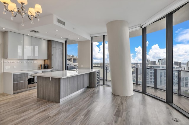 kitchen with a chandelier, a wall of windows, white cabinetry, and backsplash