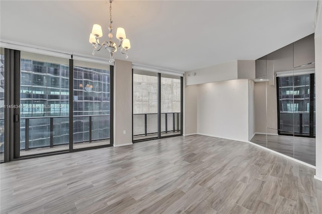 spare room with expansive windows, a chandelier, and light hardwood / wood-style floors