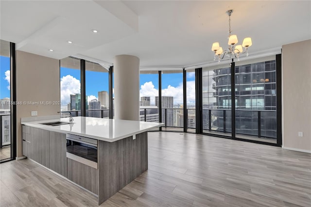 kitchen featuring expansive windows, sink, light hardwood / wood-style flooring, a chandelier, and pendant lighting