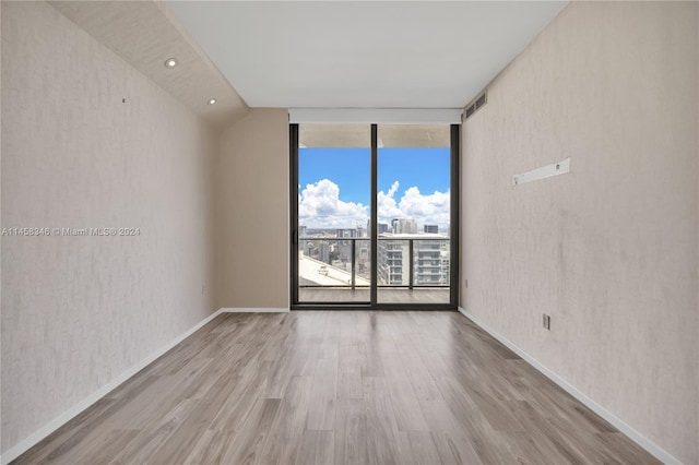 spare room featuring floor to ceiling windows and light hardwood / wood-style flooring