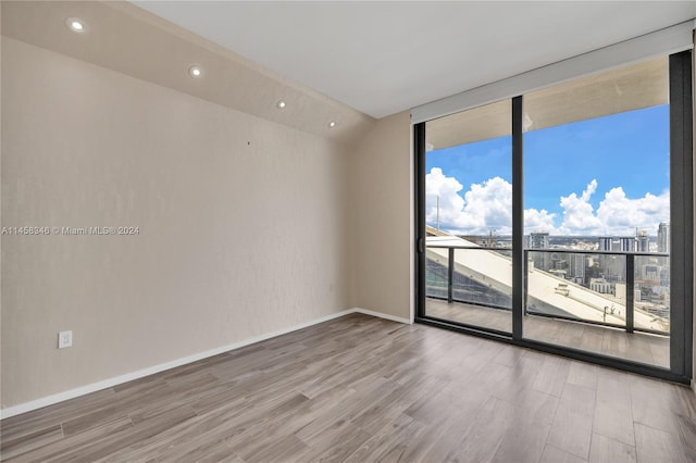 empty room featuring floor to ceiling windows and light hardwood / wood-style floors