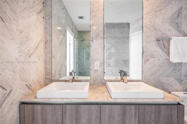 bathroom featuring tile walls, large vanity, and double sink