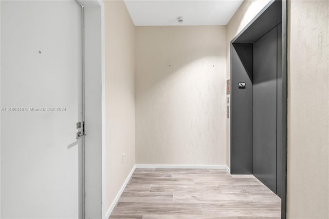 hallway with light hardwood / wood-style flooring and elevator