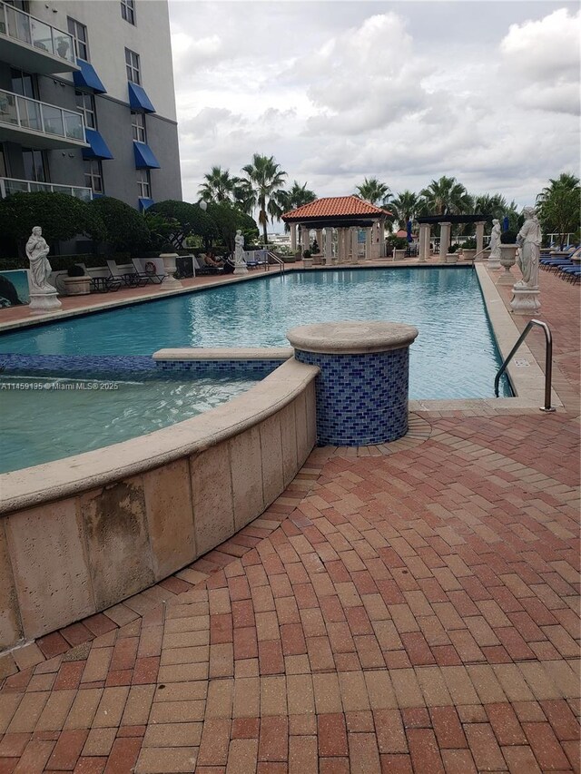 view of swimming pool with a hot tub, a gazebo, and a patio area