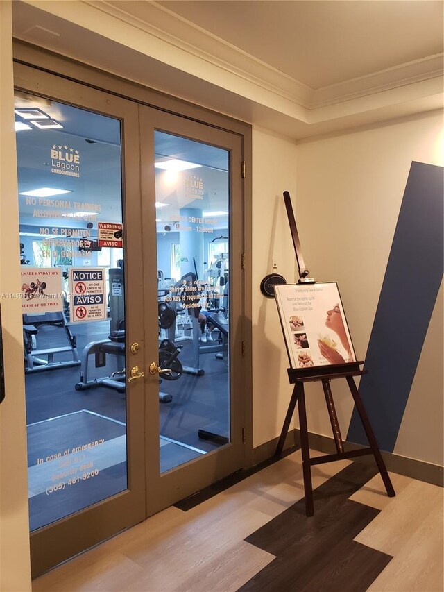 exercise room with french doors, ornamental molding, and wood-type flooring