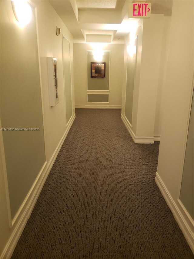 hallway featuring dark colored carpet