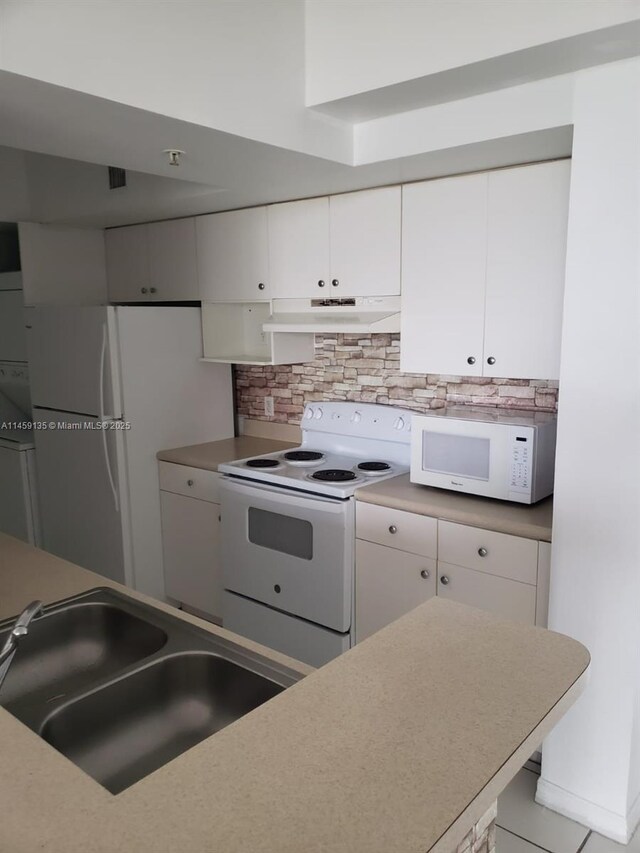 kitchen with white appliances, light tile patterned floors, and white cabinets