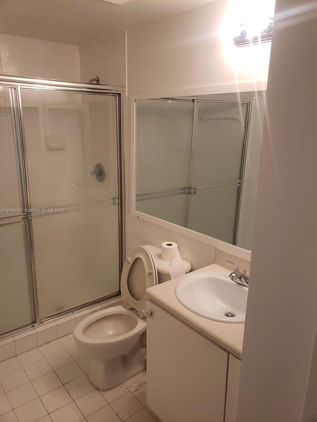 bathroom featuring a shower with door, vanity, tile patterned floors, and toilet