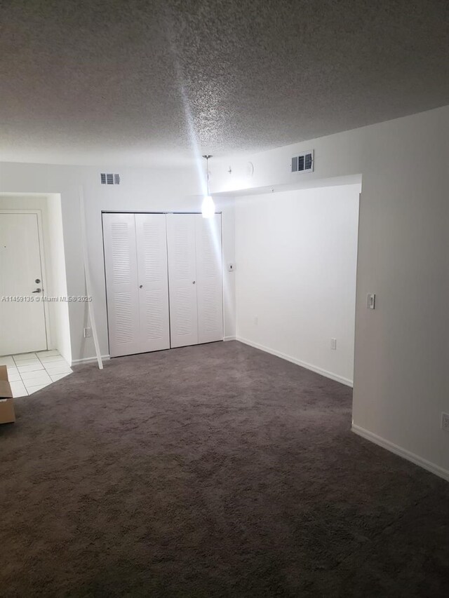 empty room with carpet and a textured ceiling