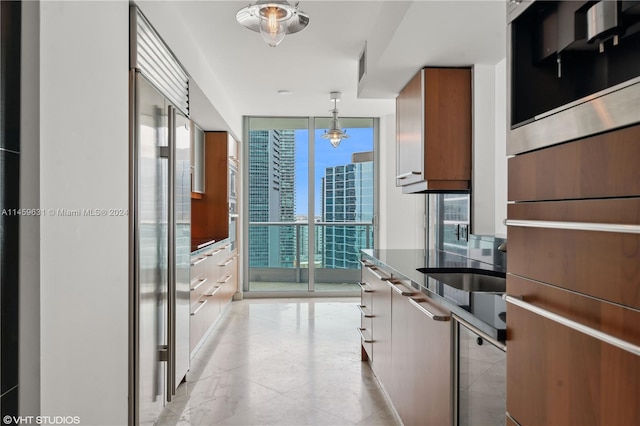 kitchen featuring pendant lighting, built in refrigerator, an inviting chandelier, and expansive windows