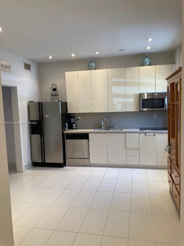 kitchen featuring white cabinetry, stainless steel appliances, sink, and light tile floors