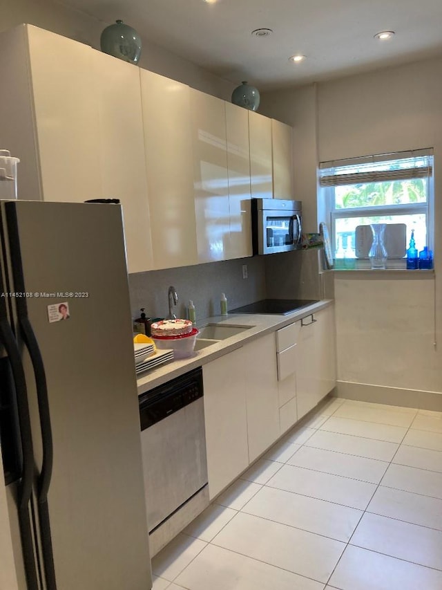 kitchen featuring white cabinets, black appliances, sink, and light tile flooring