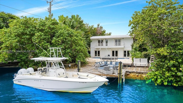 dock area with outdoor lounge area, a balcony, and a water view