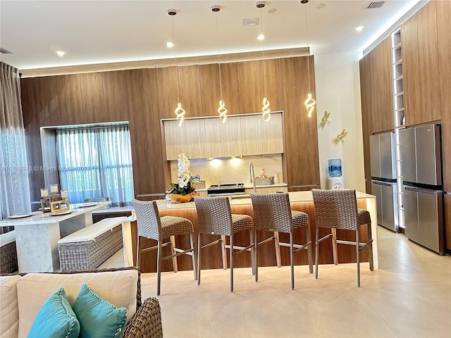 kitchen featuring wooden walls, a kitchen breakfast bar, stainless steel fridge, and pendant lighting