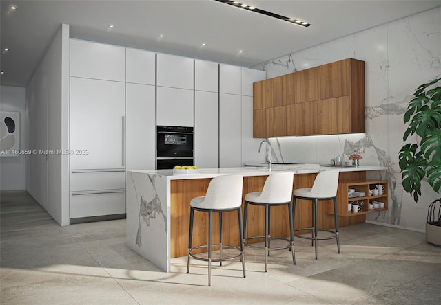 kitchen with white cabinets, double wall oven, a breakfast bar area, and sink