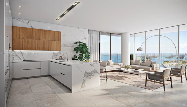 kitchen with light tile floors, light stone countertops, white cabinets, a water view, and sink