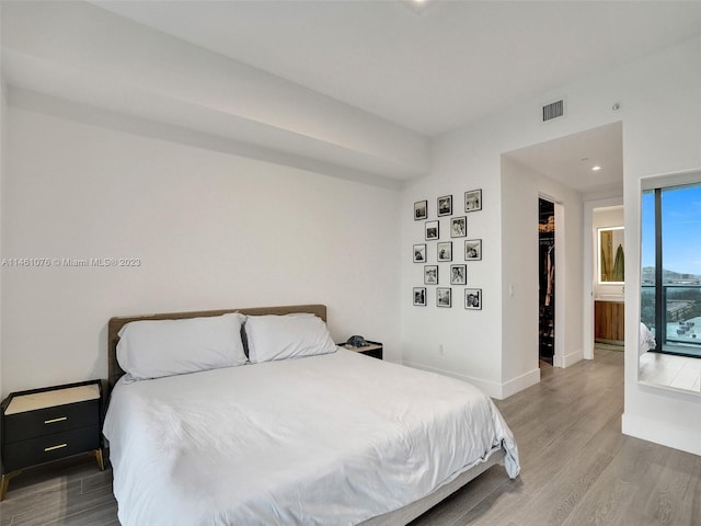 bedroom with a closet, hardwood / wood-style floors, a spacious closet, and connected bathroom