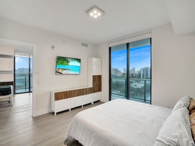 bedroom with floor to ceiling windows, access to exterior, and light wood-type flooring