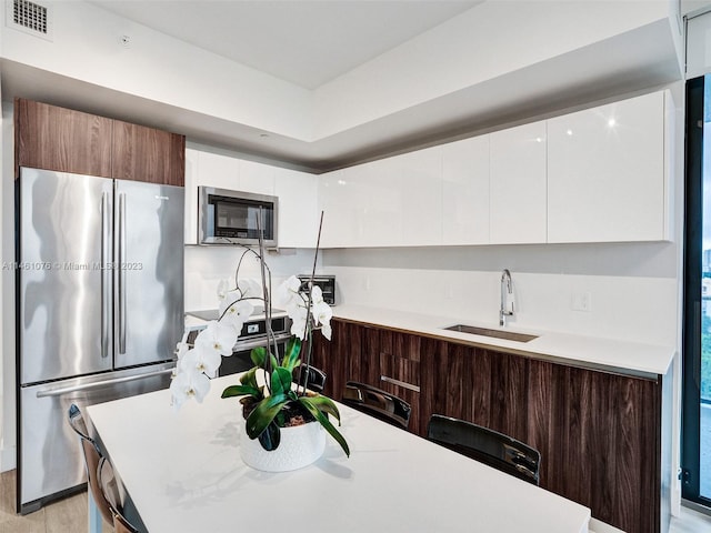 kitchen with white cabinetry, light wood-type flooring, sink, and stainless steel appliances