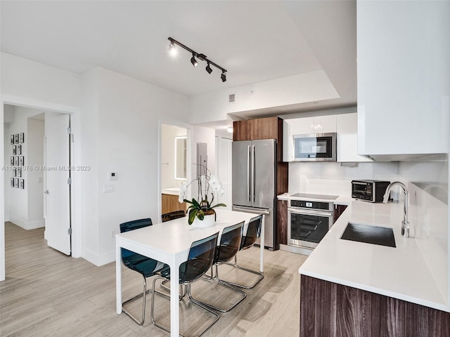 kitchen featuring white cabinetry, appliances with stainless steel finishes, track lighting, sink, and light wood-type flooring