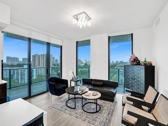 living room with a notable chandelier, light hardwood / wood-style flooring, and a wealth of natural light