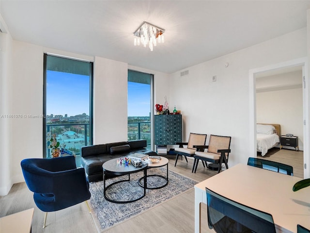 living room featuring a notable chandelier, expansive windows, and light hardwood / wood-style floors