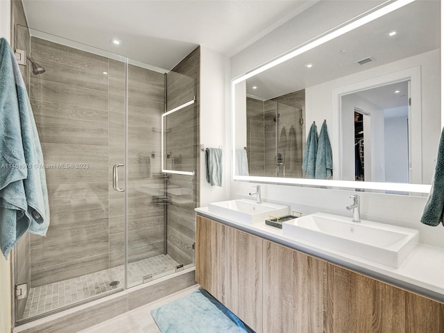 bathroom with walk in shower, double sink, and vanity with extensive cabinet space