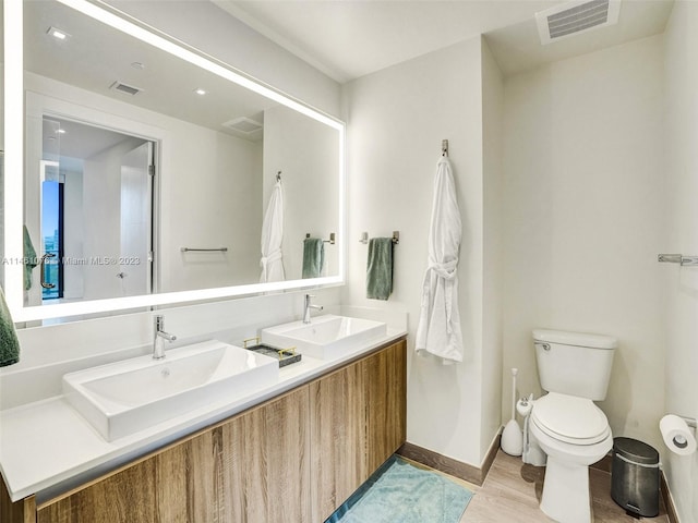 bathroom featuring toilet, double vanity, and hardwood / wood-style flooring