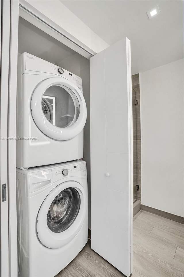 clothes washing area with light wood-type flooring and stacked washer and clothes dryer