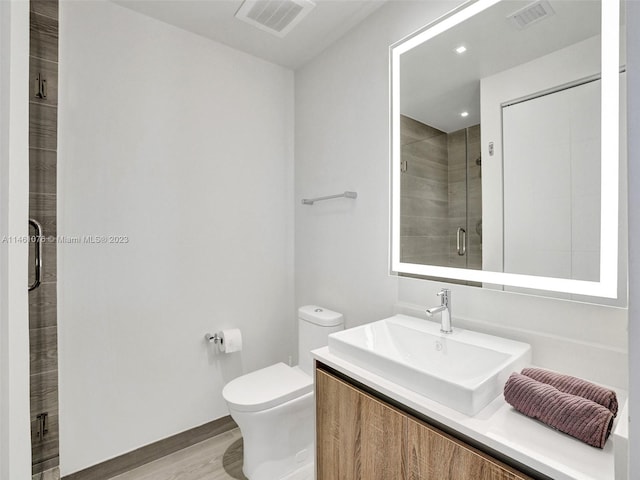 bathroom featuring vanity, a shower with shower door, hardwood / wood-style floors, and toilet