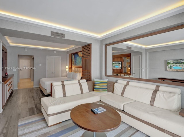 living room with a raised ceiling and light wood-type flooring