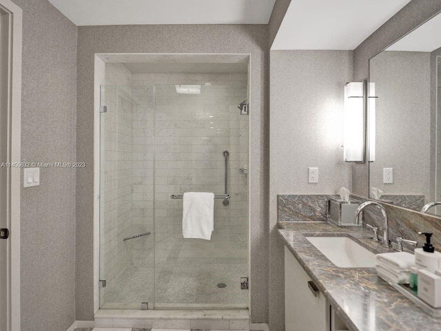 bathroom with a shower with shower door and vanity with extensive cabinet space