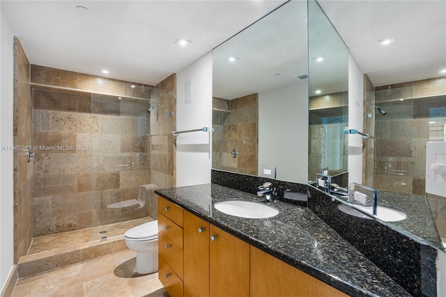 bathroom with toilet, vanity, and a tile shower