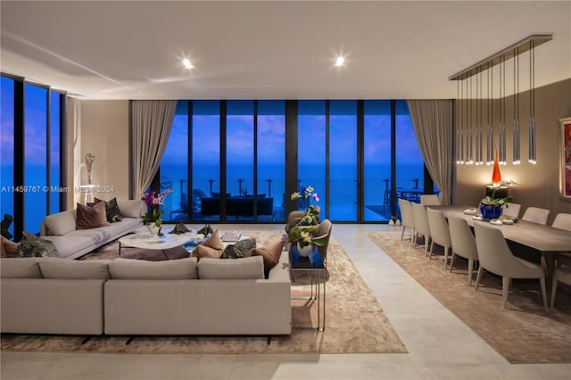 living room featuring a wall of windows, light tile flooring, and a water view