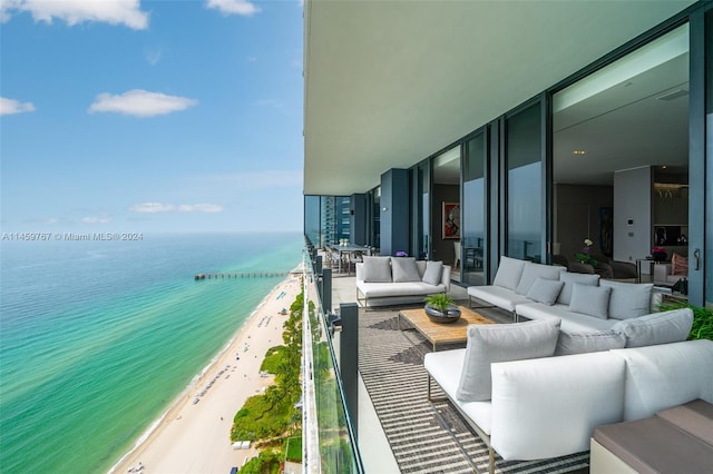 balcony featuring a beach view, a water view, and outdoor lounge area